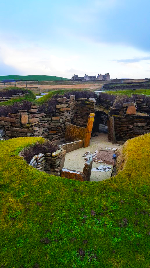 skara brae in foreground skaill house manor in distance 