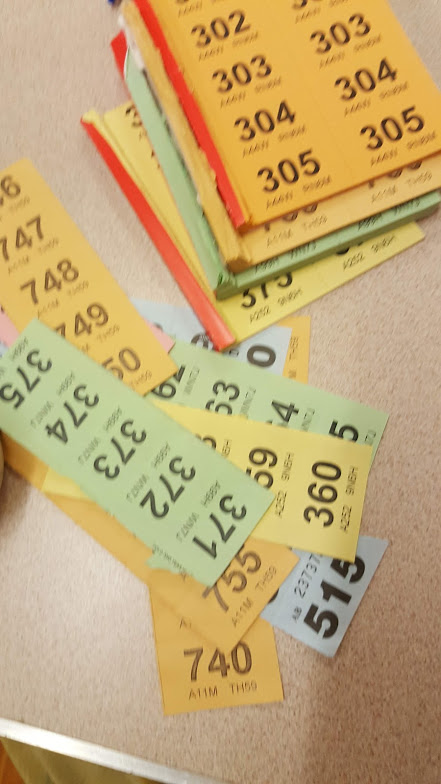 four raffle books in different colors next to a pile of tickets 