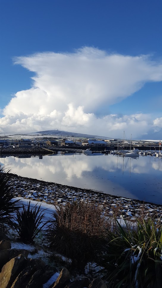 Kirkwall marina orkney with snow on the stones and hill in distance