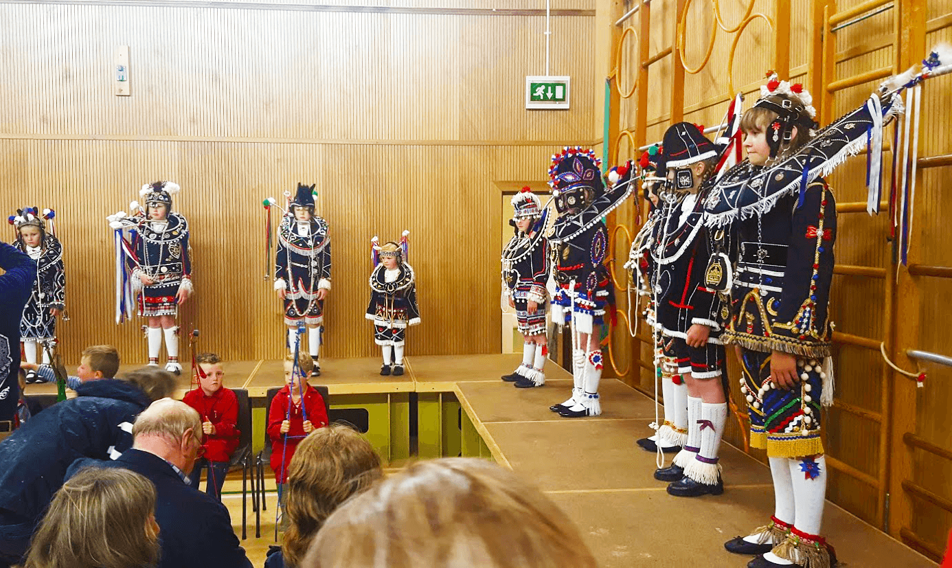 girls in elaborate black and white horse costumes stand on stage in the school hall